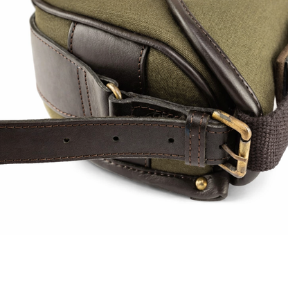 Green canvas cartridge bag leather strap details close up on white