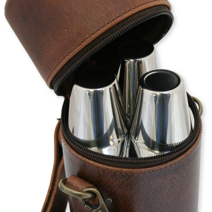 Brown leather case with silver shot glasses inside on a white background