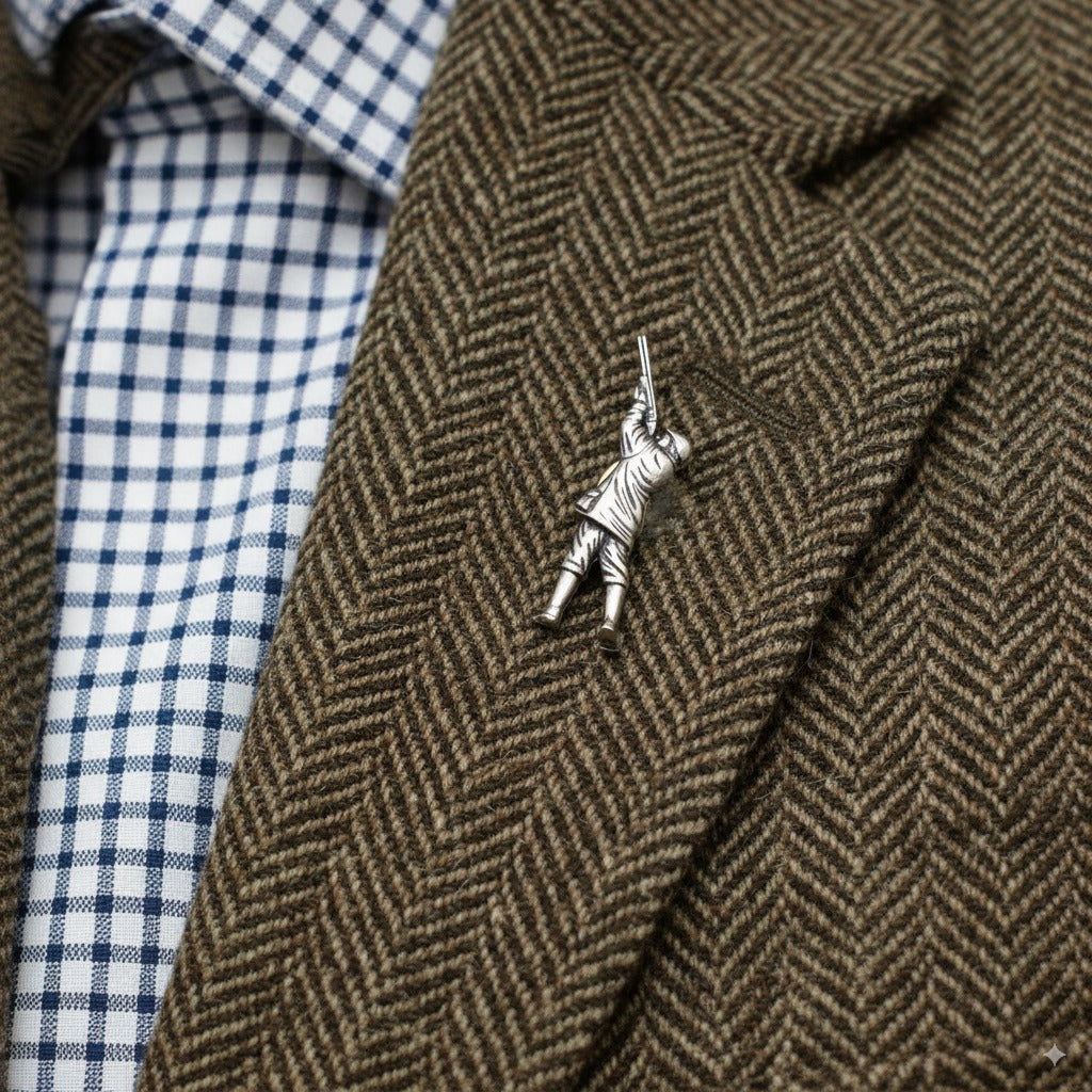 Silver lapel pin on a brown herringbone jacket with a checkered shirt.