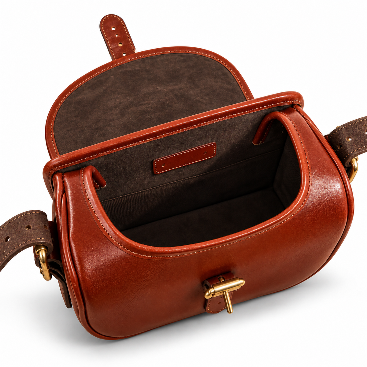 Inside of a brown leather cartridge bag with a flap closure, gold-tone buckle, shown on a clean white background.