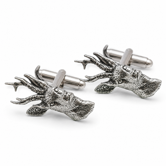 A pair of pewter metal cufflinks shaped like stag heads with detailed antlers, shown on a clean white background.