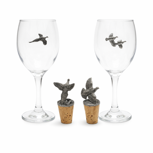 Two wine glasses with decorative bird figures on cork stoppers against a white background