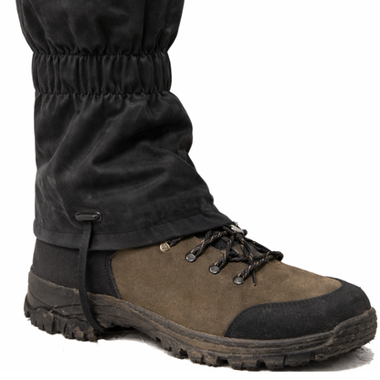 Brown hiking boot with dark gaiters on a white background