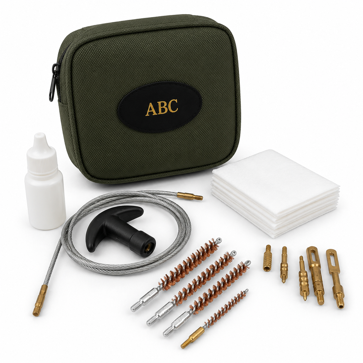 A cleaning kit laid out on a white background, including an olive green zippered case with a black oval patch and gold 'ABC' logo, a small white bottle, a coiled gray wire tool with a black T-shaped handle, several brass and silver wire brushes, and a stack of white cloths.