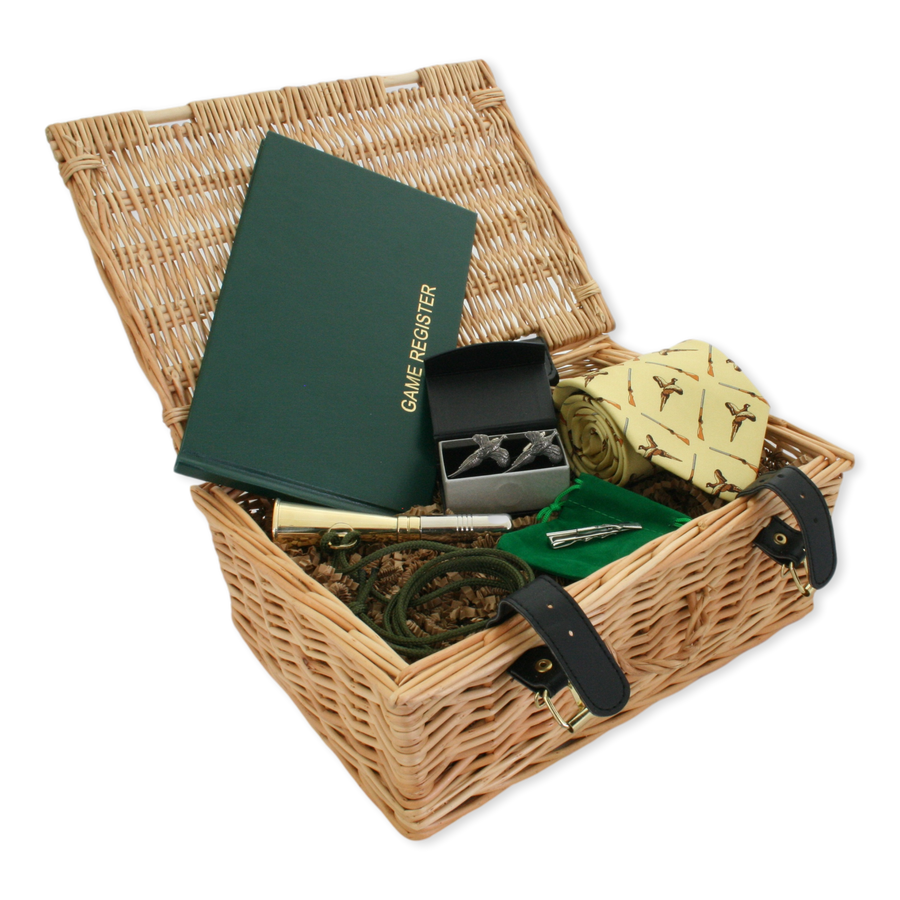 Wicker gift basket with various items including a game register, pheasant tie, and other accessories on a white background.