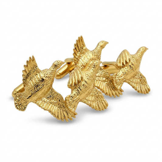 A pair of gold cufflinks shaped like flying partridges, shown on a clean white background.