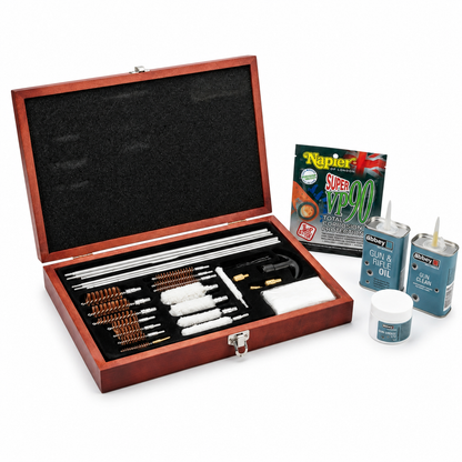 A wooden gun cleaning box filled with multiple metal cleaning or repair tools, shown open on a white studio background. Several small gun cleaning products and a Napier Super VP90 packet are placed beside the box.