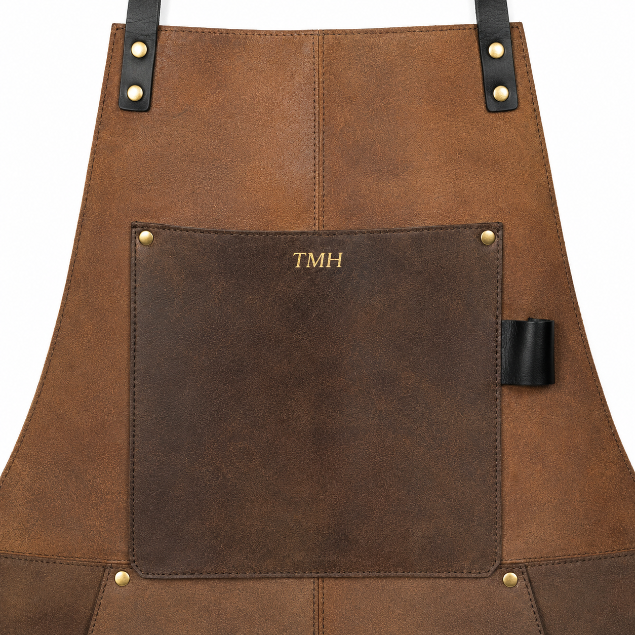 A close-up of a brown gunsmith's leather apron featuring a large front pocket with gold-embossed initials 'TMH' and black leather strap accents with brass rivets, shown on a plain white background.