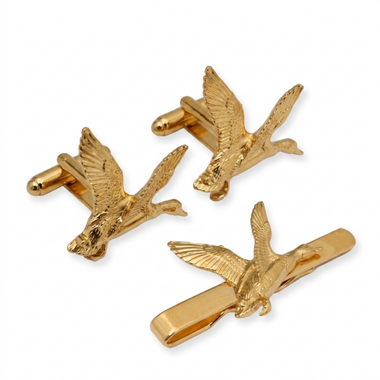 Three gold-plated mallard duck motifs arranged on a white background: two as cufflinks and one as a tie clip.