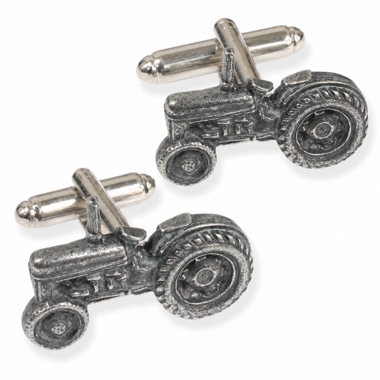 A pair of pewter cufflinks shaped like vintage tractors, shown on a clean white background.