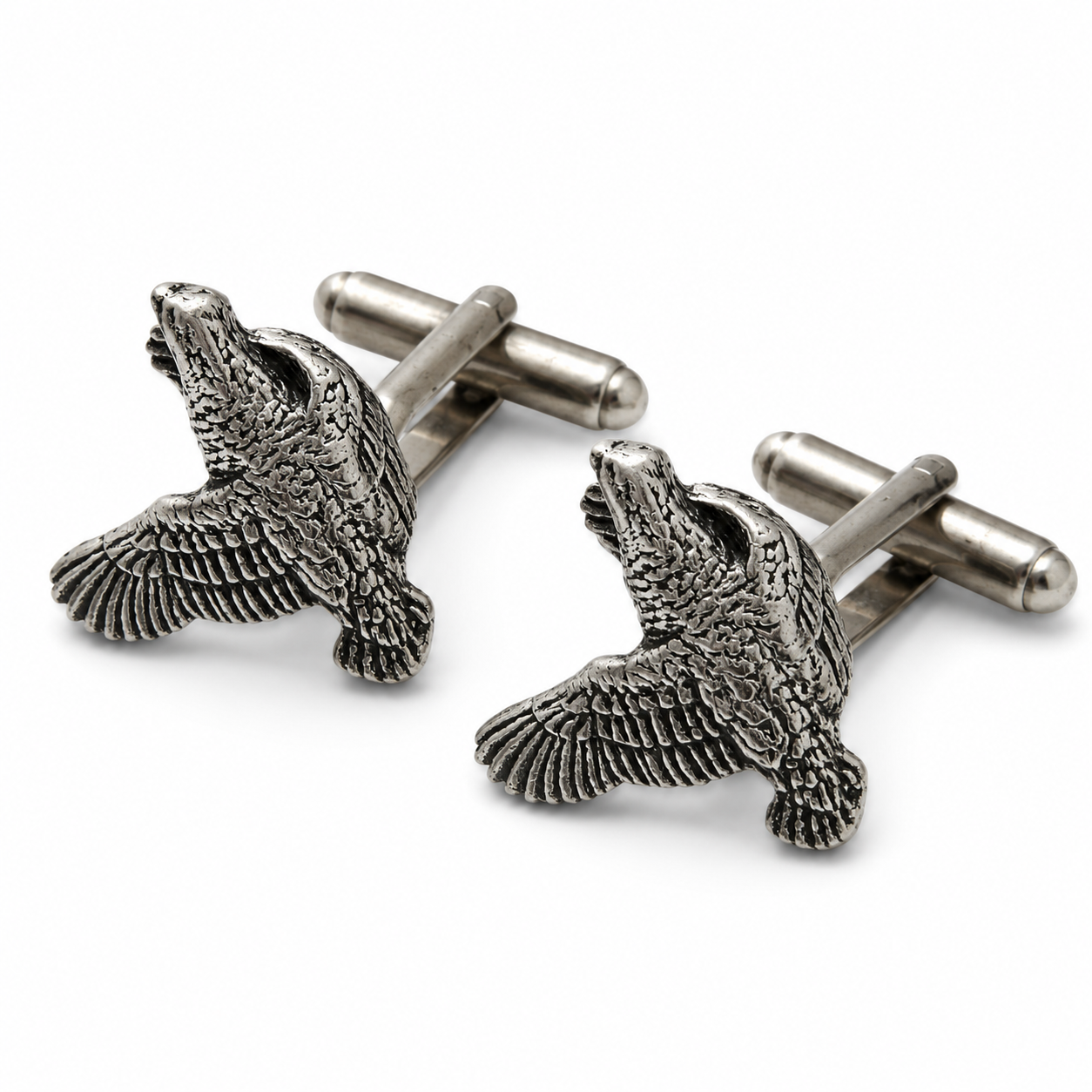 A pair of pewter cufflinks shaped like flying quails with detailed feather textures, shown on a clean white background.