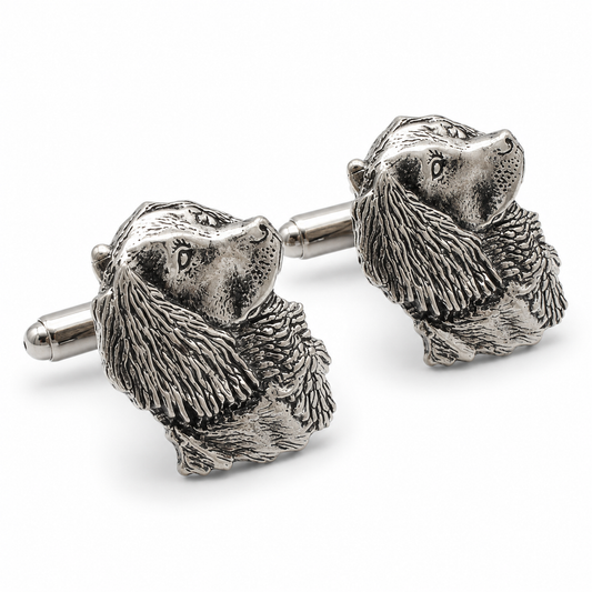 A pair of pewter cufflinks shaped like detailed spaniel heads with textured fur, shown on a clean white background.