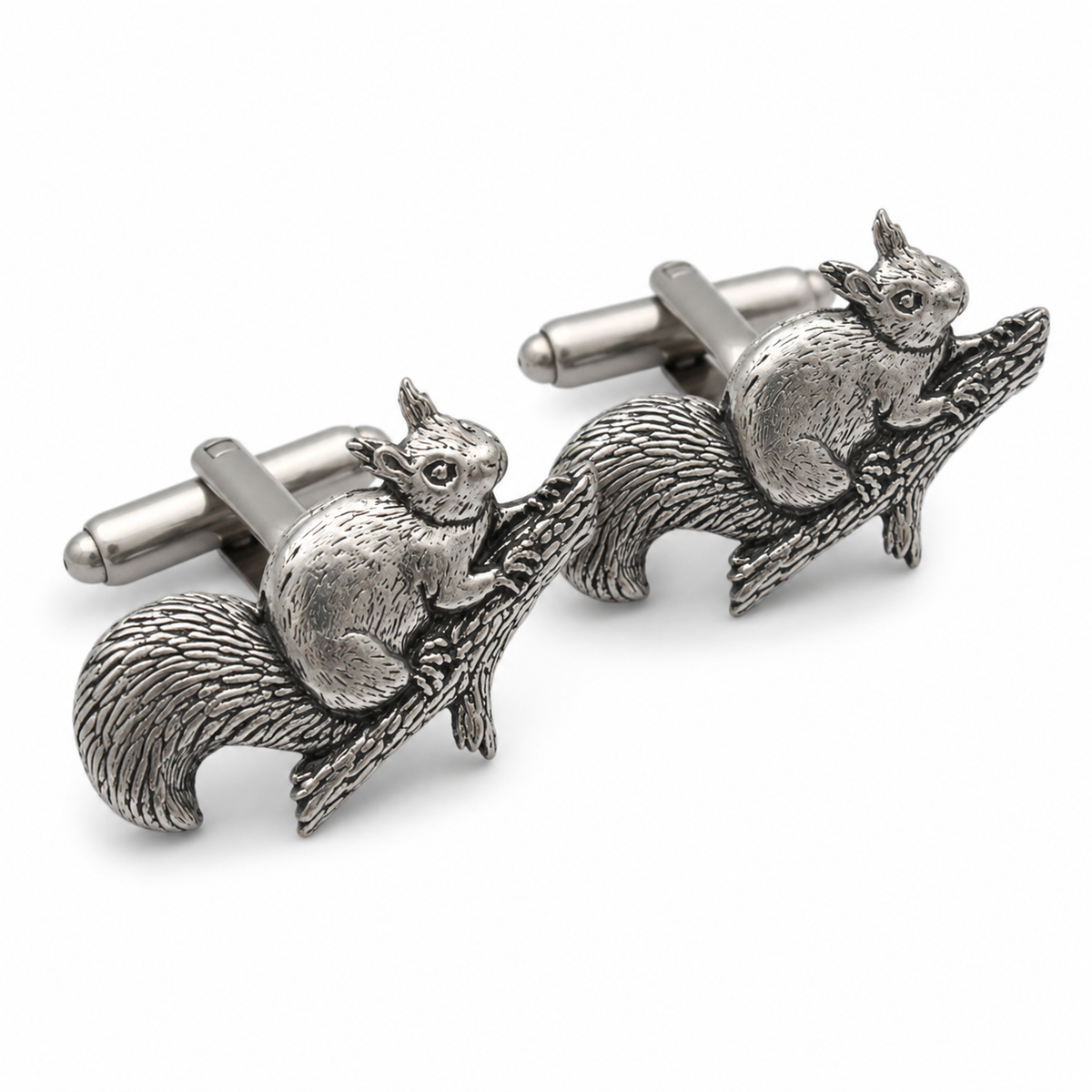 A pair of pewter cufflinks shaped like squirrels sitting on tree branches, photographed on a clean white background.