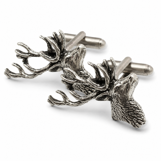 A pair of pewter metal cufflinks shaped like stag heads with detailed antlers and textured fur, shown on a clean white background.